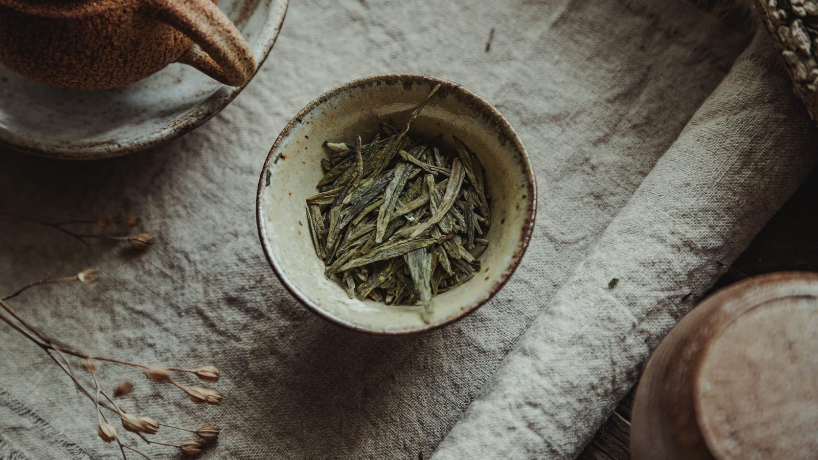 tasse avec des feuilles de thé vert séché.
