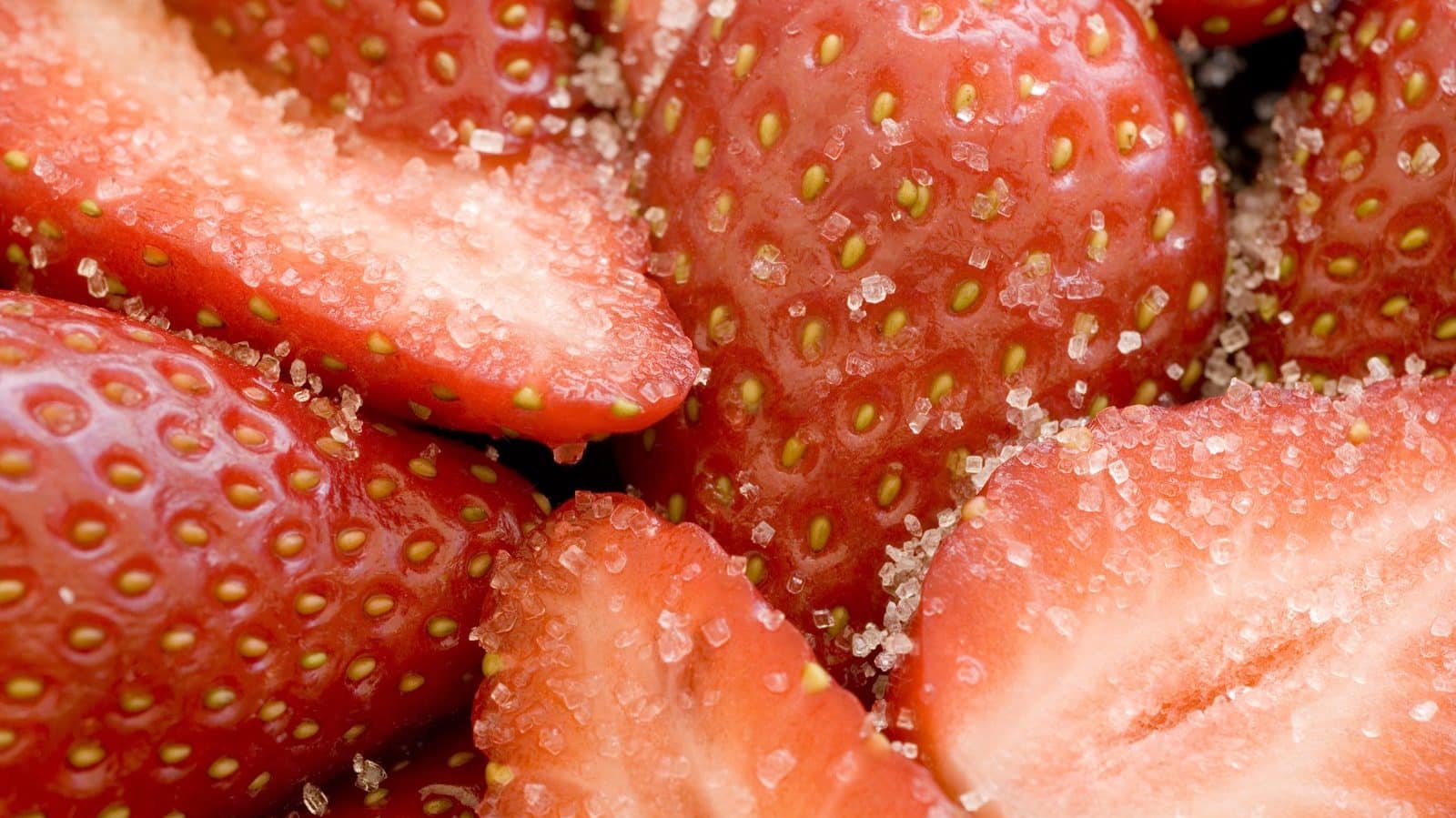 Des fraises vu de pres avec des grains de sucre dessus 
